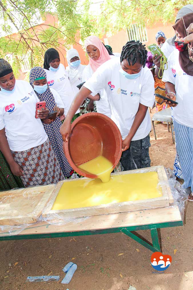 Démonstration de coulage de savon par une bénéficiaire du programme d'autonomisation économique, en présence d'autres femmes formées